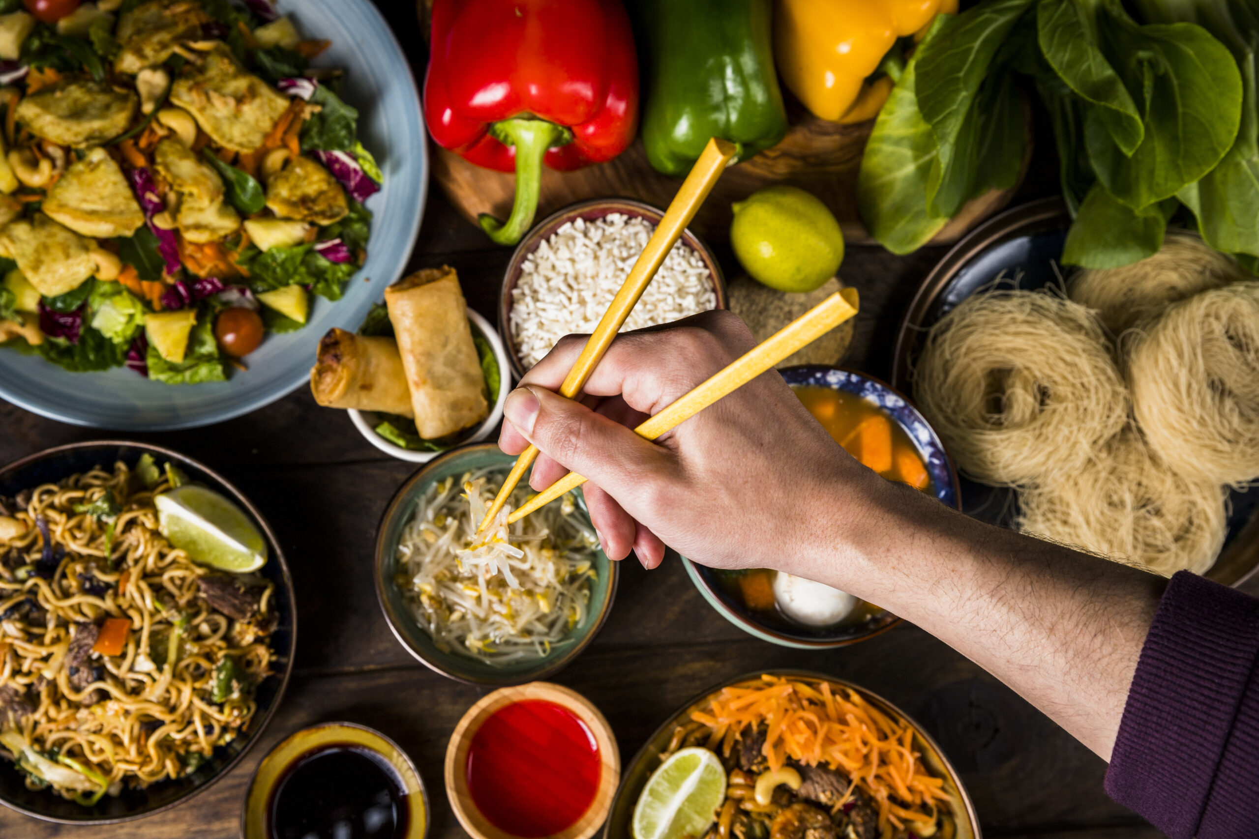 una-vista-aerea-de-la-mano-de-un-hombre-sosteniendo-palillos-sobre-la-deliciosa-comida-tailandesa